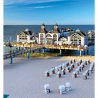 Kalenderdaten unten: 13 MÄR/APR, MO 29, DI 30, MI 31, DO 01, FR 02, SA 03, SO 04. Strand mit Seebrücke und Pavillon.