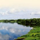 "LAND UND LEUTE" steht oben. Schöne Landschaft: Fluss mit Booten, Gras am Ufer, bewölkter Himmel.