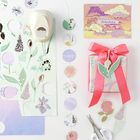 "The sky is the limit" auf einer Karte mit bunten Wolken, daneben ein verziertes Geschenk mit rotem Band und Bastelmaterial.