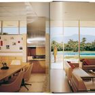 Texte zeigen Künste an der Wand. Moderner Raum mit Holzmöbeln, großer Fensterfront zum Garten mit Pool, Person draußen.