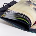 Ein aufgeschlagenes Kunstbuch mit farbenfrohen Illustrationen, darunter Wolken und farbige Figuren auf den Seiten.