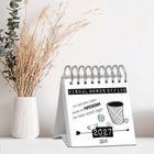 "VISUAL WORDS OFFICE. Im nächsten Leben werde ich PAPIERKRAM. Der bleibt einfach liegen. 2027. Ein Tischkalender neben Blumen."