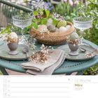 11. Woche, März 2027. Gedeckter Tisch mit gefärbten Ostereiern, Zweigen und gefalteten Stoffservietten auf grünem Tisch.