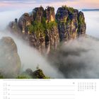 Schrammsteine in der Sächsischen Schweiz, Sachsen. Kalenderwoche 11, März. Nebel umgibt hohe Felsen unter orangefarbenem Himmel.