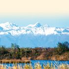 "LAND UND LEUTE" steht oben. Im Vordergrund Schilf und Wasser, dahinter schneebedeckte Berge vor hellem Himmel.