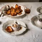 Keine Texte. Ein Tisch mit zwei Pudding-Desserts, karamellisierten Birnen, Mandelsplittern und einem Glas dunkler Flüssigkeit.