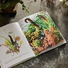 PLANTS: Celosia, Crocosmia, Cala, Craspedia. Ein Buch mit Pflanzenfotos liegt auf einem rustikalen Tisch, daneben Blumenarrangement.