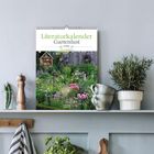 „Literaturkalender Gartenlust“. Eine Gartenszene mit bunten Blumen, zwei Tassen, Pflanzen auf einem Regal.
