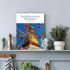 „Buddhistische Weisheiten“ steht auf einem Kalender, aufgehängt über Pflanzen auf einem Regal.