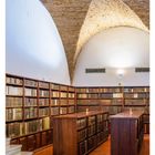 15 APRIL. Bibliothek mit alten, ledergebundenen Büchern auf Holzbüchernregalen unter einem gewölbten Ziegelsteindach.