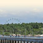 "LÄNDER UND LEUTE" oben. Ein Pier mit Personen, Wasser darunter, Bäume und ein Riesenrad im Hintergrund.