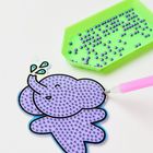 B Buchstaben in blauen Tropfen. Lila Elefantenanhänger mit Perlen und grünem Tablett voller violetter Perlen.