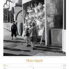 März/April Kalenderblatt zeigt Kinder vor einem Puppenstand auf einer Kirmes, umgeben von Ballettpuppen.