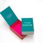 TEXT: "Typodarium 2027. TYPO DARIUM." Ein geöffneter Karton mit pinkem Innenraum und einem Kalenderstapel.