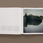 Seite mit Text links und Foto rechts. Foto zeigt eine ruhige Flusslandschaft mit Bäumen am Ufer im weichen Licht.