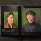 Ein geöffnetes Buch zeigt ein Gemälde mit einer bunten Himmelsdarstellung und vielen Engeln um eine zentrale Figur am Kreuz.