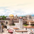 LAND UND LEUTE. Eine alte Festung mit Kuppeln aus Gold und Rot, umgeben von Türmen, Gebäuden und Gärten.