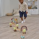 Ein Kind in Hemd und Shorts spielt mit einer Holzkugelbahn in einem freundlich eingerichteten Zimmer.