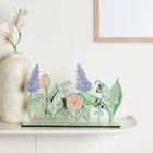 Keine erkennbaren Texte. Dekorative Blumenskulptur auf einem Regal vor einem schlichten Hintergrund.