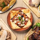 Verschiedene Gerichte auf Holzbrettern: Croissants mit Gemüse, belegte Brote, Kartoffelchips, gebratenes Hähnchen.