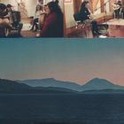 Eine Gruppe von Musikern in einem Studio, einige mit Instrumenten, darunter ein Akkordeon, Gitarre und eine Frau am Mikrofon. Darunter eine Landschaft mit Hügeln am Horizont und einer Wasserfläche im Vordergrund.