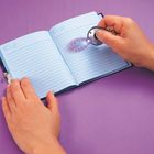 „SECRET NOTES“ ist in einem offenen Notizbuch zu lesen. Eine Hand beleuchtet es mit einer kleinen Taschenlampe.