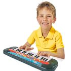 Ein Junge in gelbem Shirt spielt fröhlich auf einem bunten Spielzeugkeyboard.