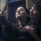 Es gibt keinen erkennbaren Text. Eine Person hält einen Spiegel, eine andere Person umarmt sie von hinten.