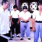 Zu sehen sind sechs Männer in Kampfkunstkleidung. Im Vordergrund links steht ein Mann mit Fächer, rechts ein Mann in Kampfhaltung.