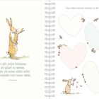 Links steht: „Es gibt nichts Schöneres, als geliebt zu werden...“ Rechts: „Diese lieben Wünsche möchten wir dir mitgeben:“ Illustration mit Hasen und Blumen.