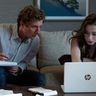 Ein Mann und eine Frau arbeiten zusammen an einem Laptop in einem Wohnzimmer. Er schreibt, sie zeigt auf den Bildschirm.
