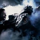 Ein Mensch schreit eine große, reptilartige Kreatur an, umgeben von dichtem Nebel. Es ist düster beleuchtet.