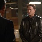 Zwei Männer in einem Lagerraum. Links ist nur der Rücken eines Mannes sichtbar. Der andere trägt eine schwarze Lederjacke.