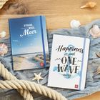 Zwei Notizbücher, links "Strand, Wind, Meer", rechts "Happiness is just one wave away". Sanddünen, Seile, Muscheln.