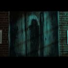 Links der Text "QUISQUAM..." auf einem gerahmten Bild; dunkle Gestalt in der Mitte; rechts ein weiteres Bild.