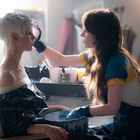 Zwei Frauen in einem Studio, eine sitzt ruhig mit Gips auf dem Kopf, die andere trägt Handschuhe und arbeitet konzentriert.