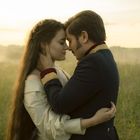 Es gibt keinen Text im Bild. Ein Paar umarmt sich innig auf einer Wiese bei Sonnenuntergang.