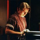 Eine Person in einem gemusterten Hemd betrachtet eine Maschine in einem schwach beleuchteten Raum.