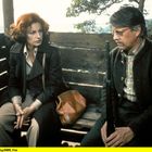 20010208155641 SWR F02. Eine Frau und ein Mann sitzen in einem Holzwagen. Der Mann hält ein Gewehr, beide wirken ernst.