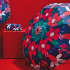 Bunte Illustration mit einem Regenschirm und einer Tasche, beide mit lebendigen, roten und grünen Blumen auf blauem Hintergrund.