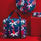 Taschen mit buntem Blumenmuster auf rotem Hintergrund. Ein Rucksack, eine runde Tasche und ein Täschchen sind sichtbar.