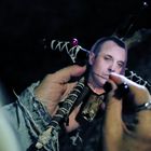 Es gibt keinen erkennbaren Text. Eine Hand hält eine Puppe mit einem Gesichtsfoto, während eine Nadel in die Puppe gesteckt wird.