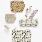 Etiketten mit „reed x reed“ auf Stofftäschchen mit floralen Mustern, Stifte und Radiergummis in Pastellfarben.