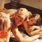 "Ich spüre deine Haut" vor orangefarbenem Kreis. Drei Personen liegen eng aneinander auf kariertem Stoff.