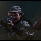 Zwei bewaffnete Männer zielen mit Gewehren. Einer trägt eine Mütze, der andere eine Polizeiuniform.