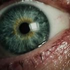 Kein Text vorhanden. Nahaufnahme eines menschlichen Auges mit blau-grüner Iris und Details der Haut.