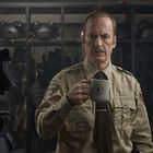 Ein Mann in einer Sheriff-Uniform hält eine Tasse mit einem Sheriff-Logo. Im Hintergrund sind Helme zu sehen.