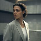 Es gibt keinen erkennbaren Text. Eine Frau im grauen Blazer schaut nach links; Hintergrund ist modern und minimalistisch.