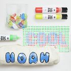 "NOAH" in blauen Buchstaben auf einer Stofftasche, bunte Stifte und Punktkunst daneben.