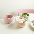 Drei Filzschalen: rosa, grün und beige. Grüne mit Birnen, beige mit Eiern gefüllt; rosa leer. Pinker Stuhl im Hintergrund.